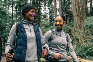 Couple wearing neon color sunscreen while taking a walk in nature.